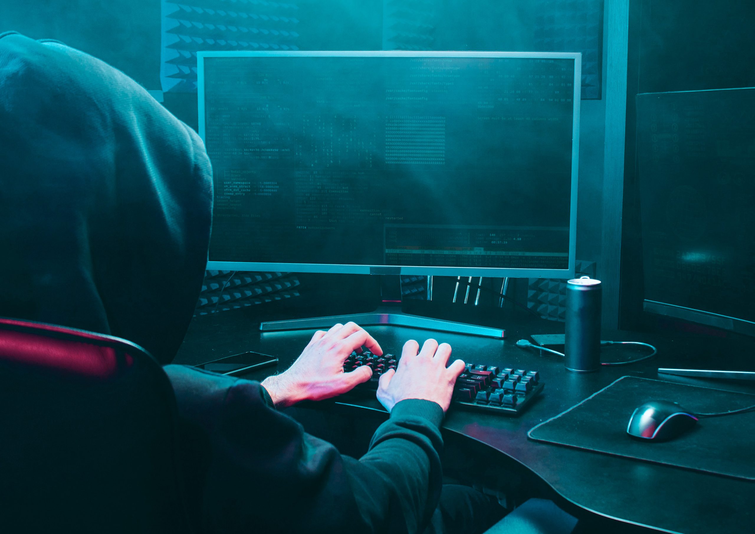 Cyberattacke aufgrund eines unsicheren Passworts: Hacker sitzt vorm PC und programmiert